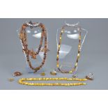 Two amber beaded necklaces together with five white metal and amber rings together with a white meta