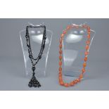An orange agate faceted beaded necklace together with a black glass beaded necklace.
