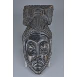 An African carved hardwood mask hanging. 33cm length.