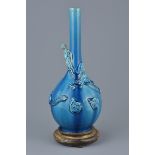 Porcelain blue ground bottle vase wrapped with a molded dragon on a Wooden Stand, 32cms high