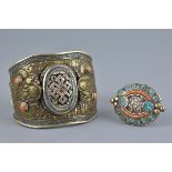 A large Tibetan metal bangle with coral coloured stones decorated with two dragons and incised decor