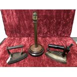 An antique cast iron flat smoothing iron, a vintage early electric iron and a lamp stand.