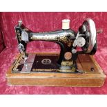 A hand driven singer sewing machine and wooden carry case.