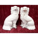 A pair of Staffordshire dogs in white with gold gilding.