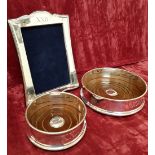 A pair of solid silver wine coasters and an Art Deco style solid silver picture frame.