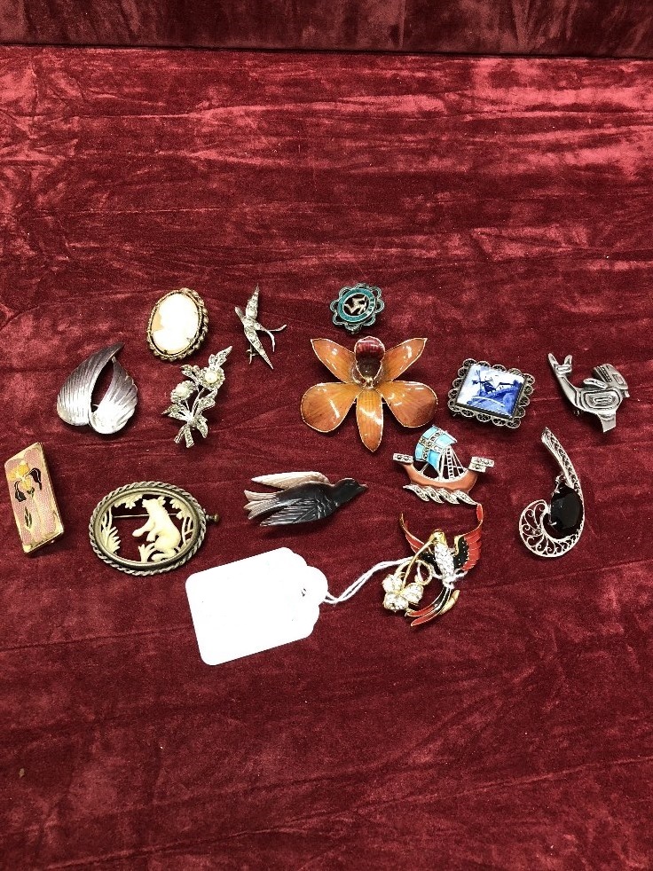 A collection of brooches including silver and enamel.