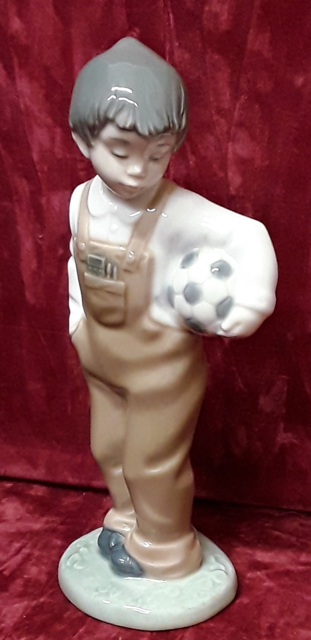 A Lladro Nao Daisa 1988 figurine of boy with a football.