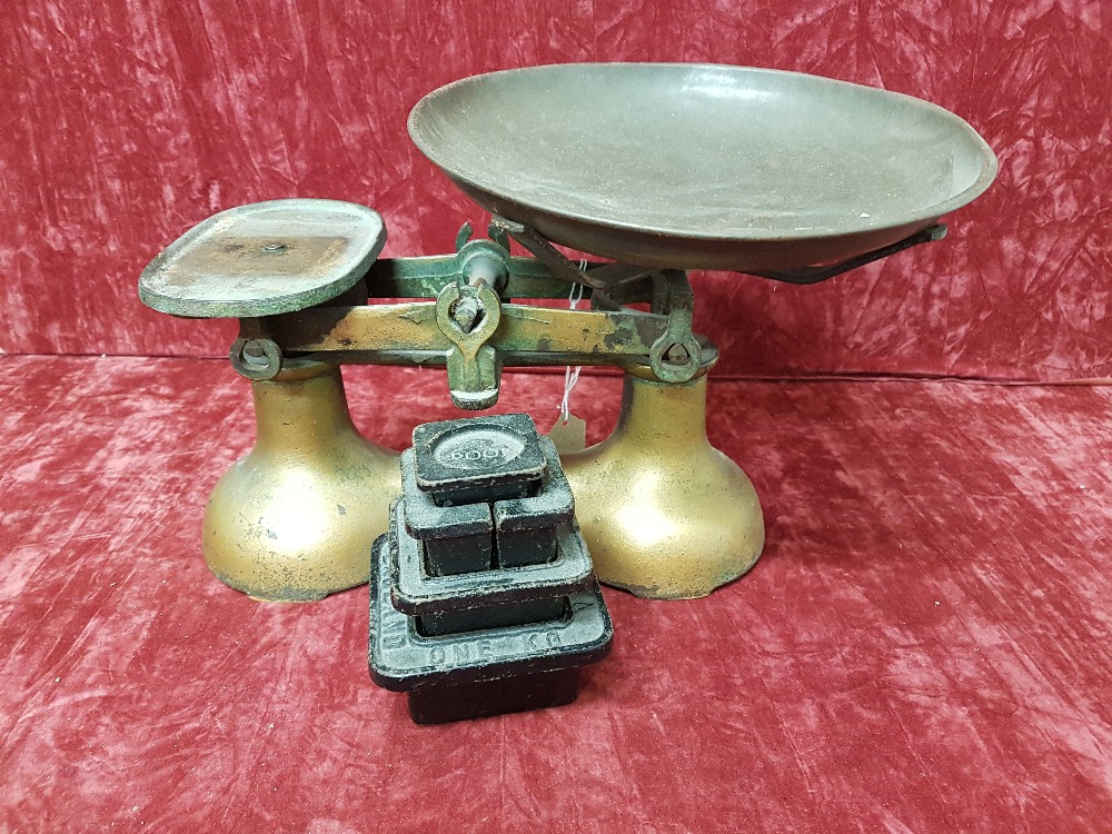 A small metal set of scales with a metal pan and a collection of metric weights.