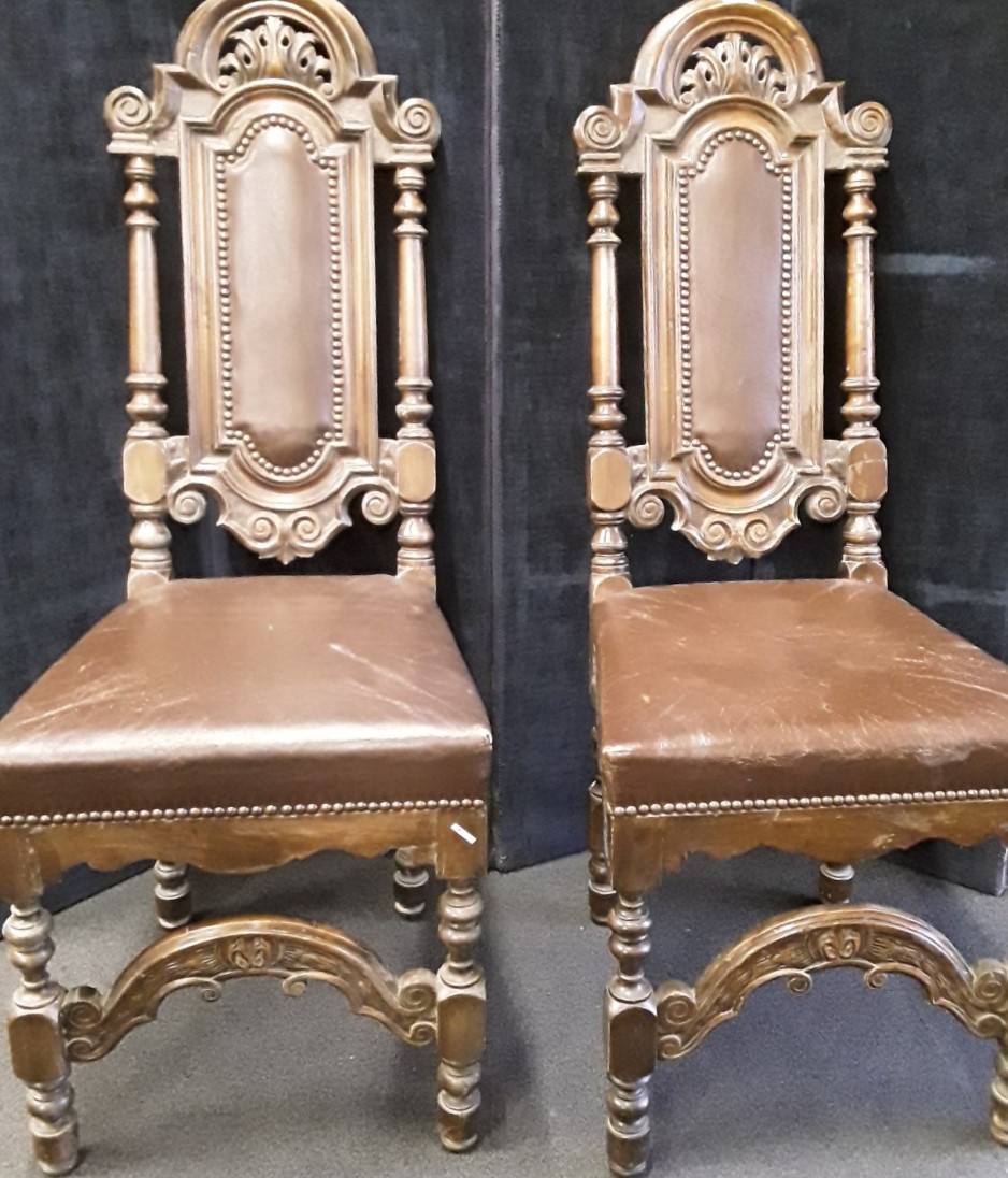 Two high back carved oak chairs with leather inserts into backs and leather seats.