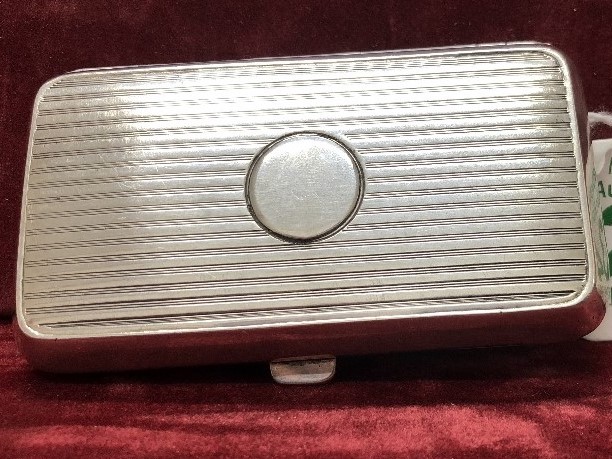 A silver cigarette tin with engine turned decoration.