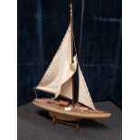 A model yacht under sail on a stand.