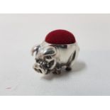 A silver pincushion in the form of a pig.