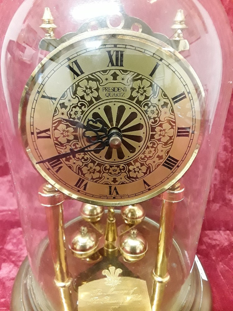 A revolving pendulum glass domed mantel clock with two brass supports.
