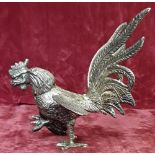 A white metal Rooster in walking motion.