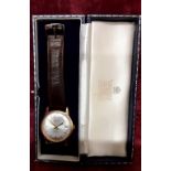 A 9ct gold Garrard automatic watch with brown leather strap. In original box.