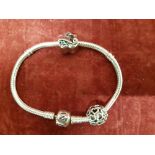 A silver Pandora bracelet marked S925 with two silver charms.