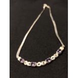 A matching silver flat link necklace and bracelet, both set with four purple gemstones.