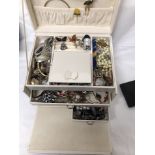 A white jewellery box containing a variety of costume jewellery.