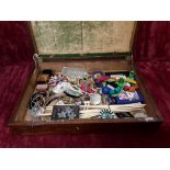 A wooden box containing an assortment of vintage costume jewellery and small collectables.