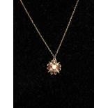 A 9k yellow gold flower shaped necklace pendent set with a central pearl and four (possible) rubies.
