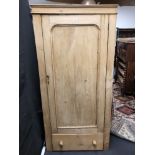 A pine single door wardrobe or kitchen cupboard with single drawer to the base.