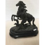 A hollow bronze statue of a man leading a horse, mounted on an ebonised base.