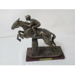 A figurine of Desert Orchid with rider jumping a fence.