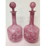 A pair of matching pink and white glass decanters.