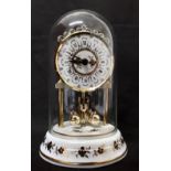 A domed revolving pendulum mantel clock with a porcelain base.