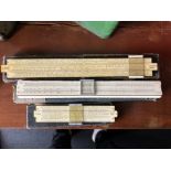 A set of three boxed slide rules.