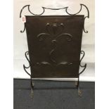 A hammered copper Rennie Mackintosh style fire screen mounted in an iron frame.