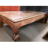 A large hardwood coffee table with glass top.