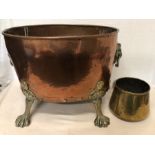 A large Victorian copper and brass log basket with lion head handles and raised on paw feet.