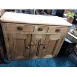 A pine dresser base with three drawers over two cupboards.