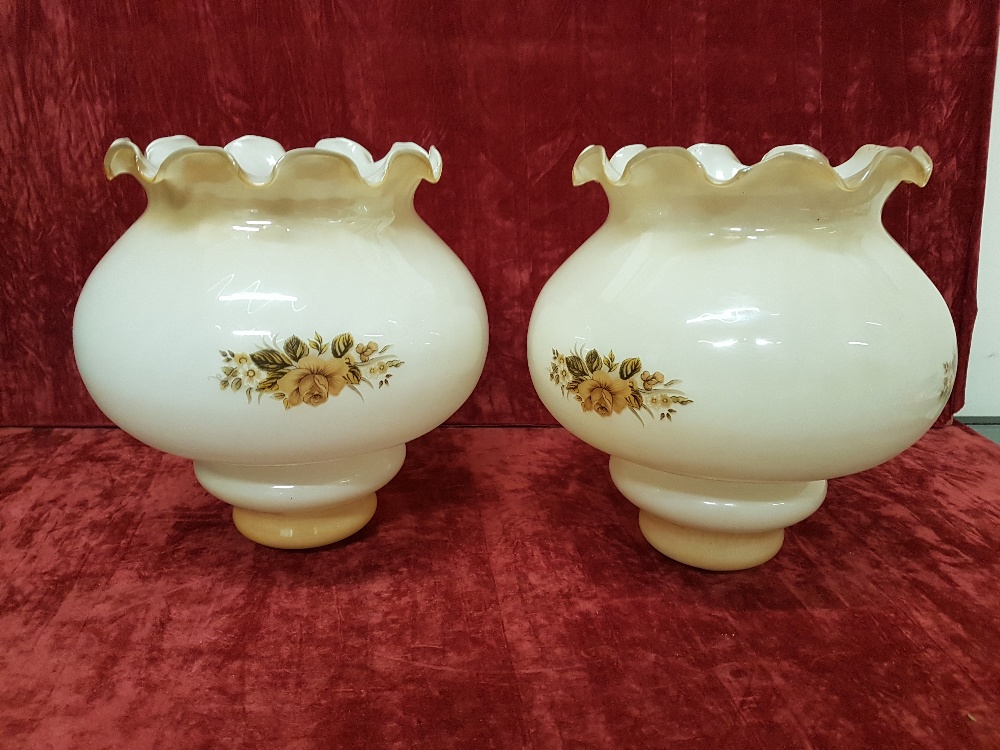 A pair of opaline lampshades decorated with transfer painting of a rose bud.