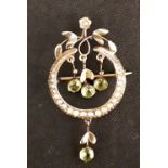 A 9ct yellow gold circular brooch set with four small peridot stone drops.