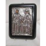 A silver framed religious icon depicting three figures on a black ebonised wooden back,