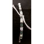 A silver line bracelet set with opaline and emerald panels.