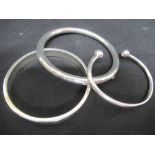 Three silver bangles of varying designs.