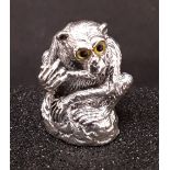 A silver pincushion in the form of a monkey, set with glass eyes.