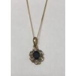 A 9ct yellow gold pendant in the form of a daisy set with a large black sapphire and diamond chips.