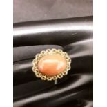 Yellow metal ring with coral cabochon.