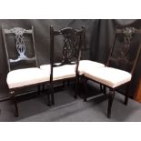 A set of four dining chairs of ebonised wood with upholstered seats.