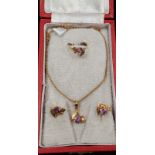 A string of purple quartz beads along with a gold plated and amethyst necklace and earring set.