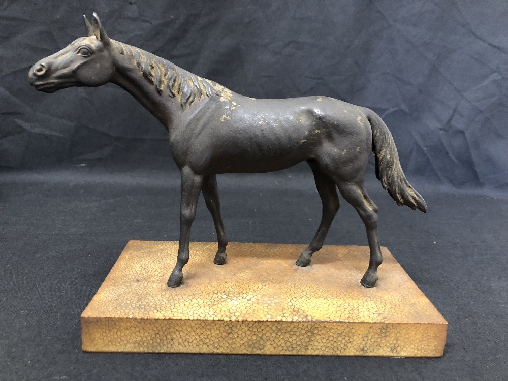 A metal horse painted as bronze, mounted on a wooden base.