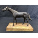 A metal horse painted as bronze, mounted on a wooden base.