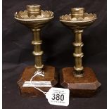 A pair of mid 19th Century hand crafted brass candlesticks mounted on wooden bases.