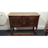 A Jacobean style oak sideboard with two cupboards each decorated with carved faces.