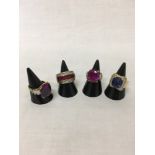 A collection of four silver dress rings with gold set with CZs, blue and red amethysts.