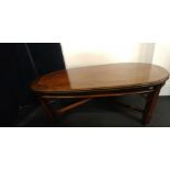 A contemporary light oak oval coffee table raised on block supports.